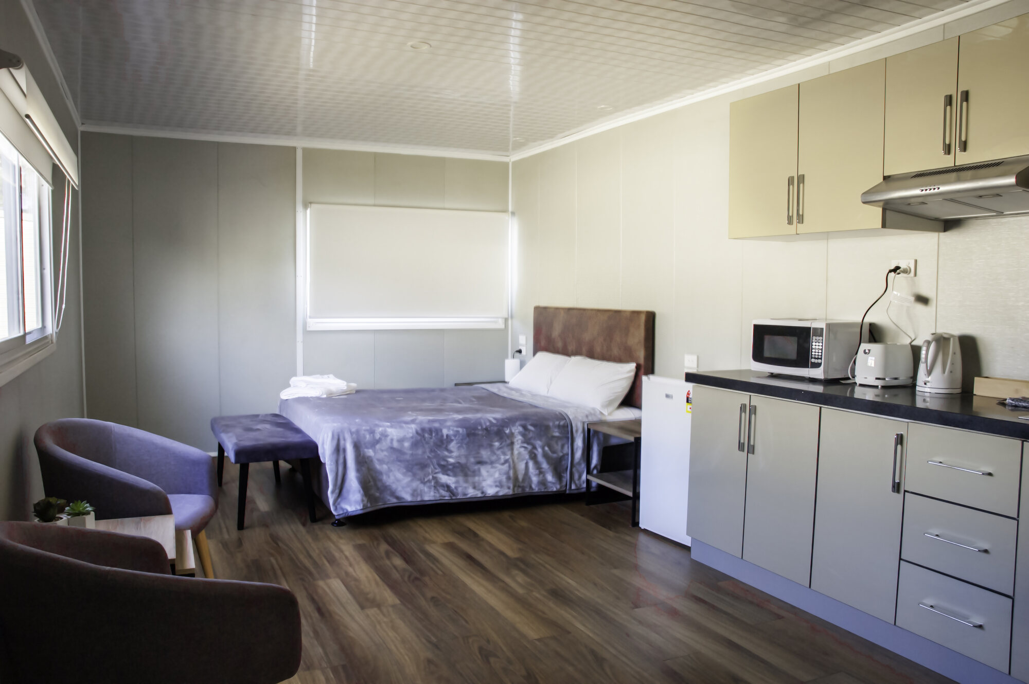 Comfortable queen bed, armchairs and kitchenette inside a Bellhaven villa